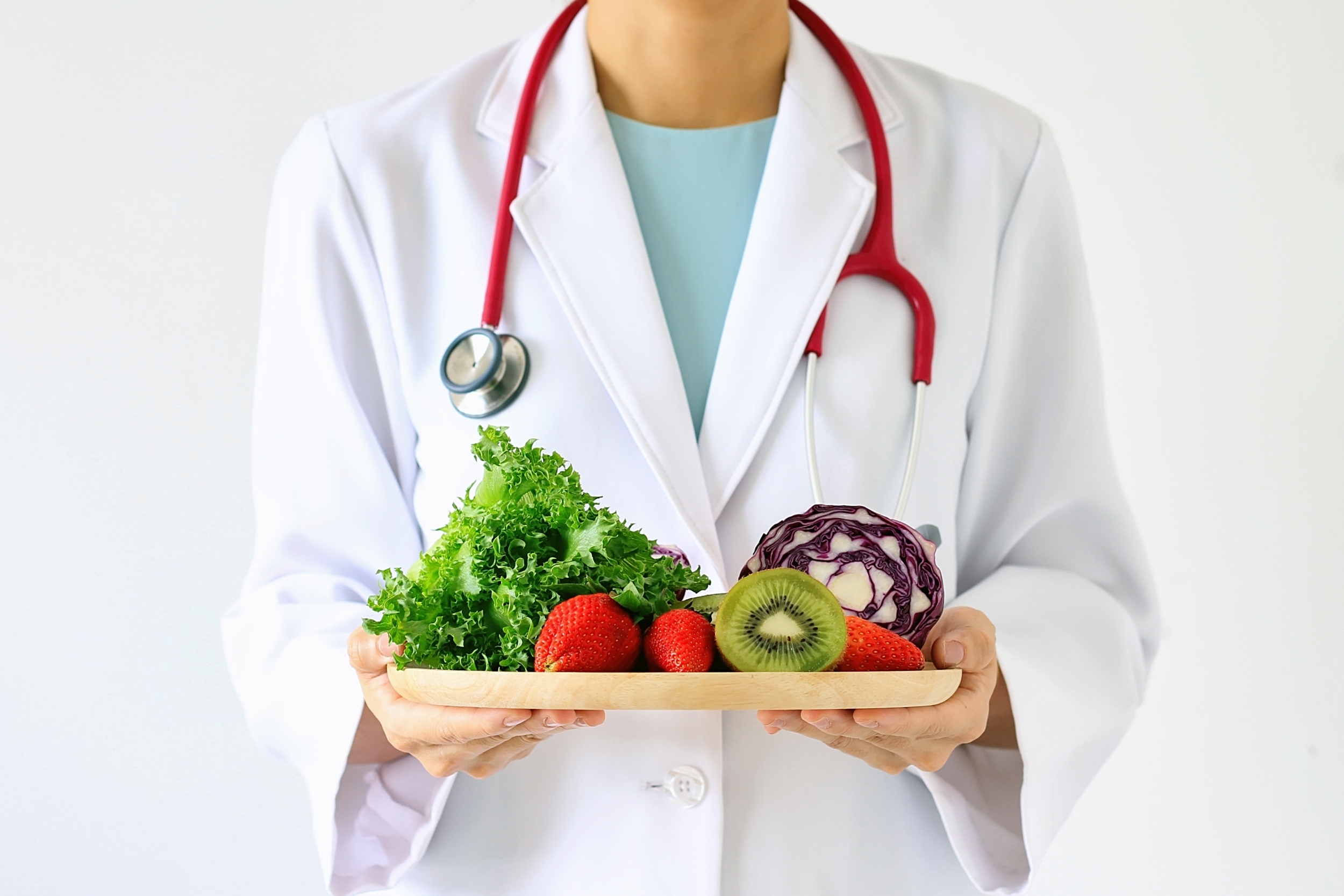 Doctor holding a plate of fruits and vegetables.